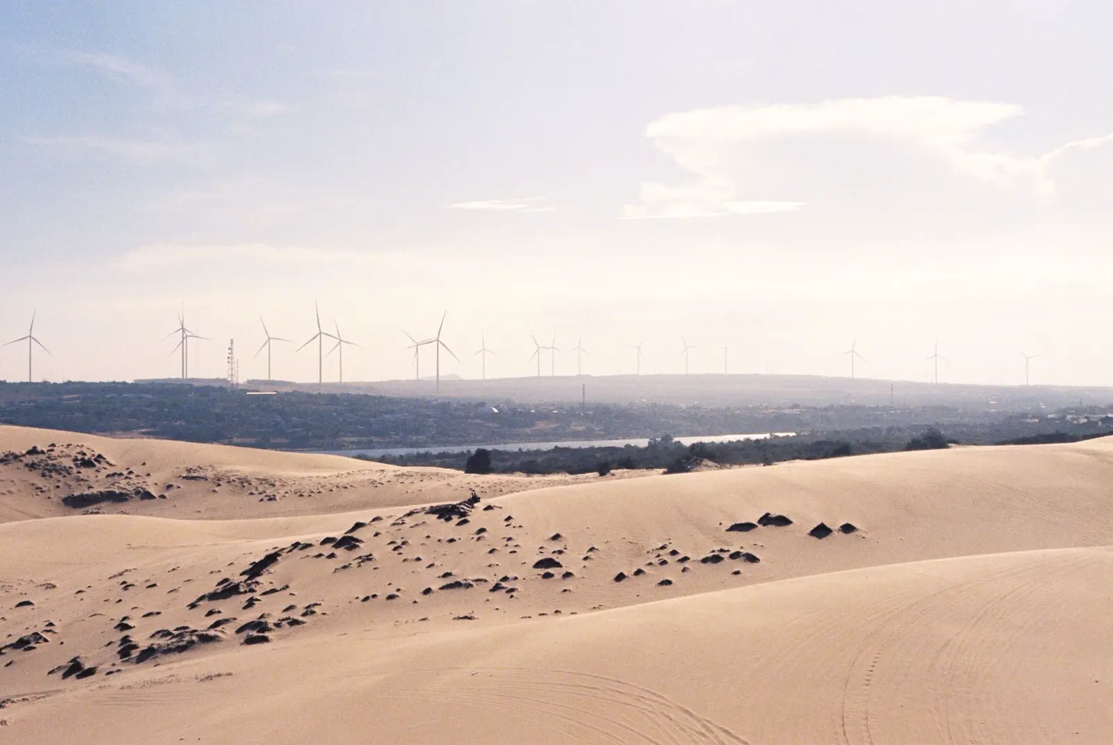 A row of wind turbines in a sandy desert under a clear sky.
