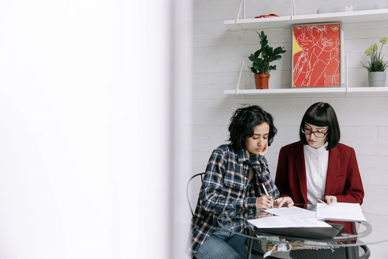 Two people at a round table reviewing printed pages together.