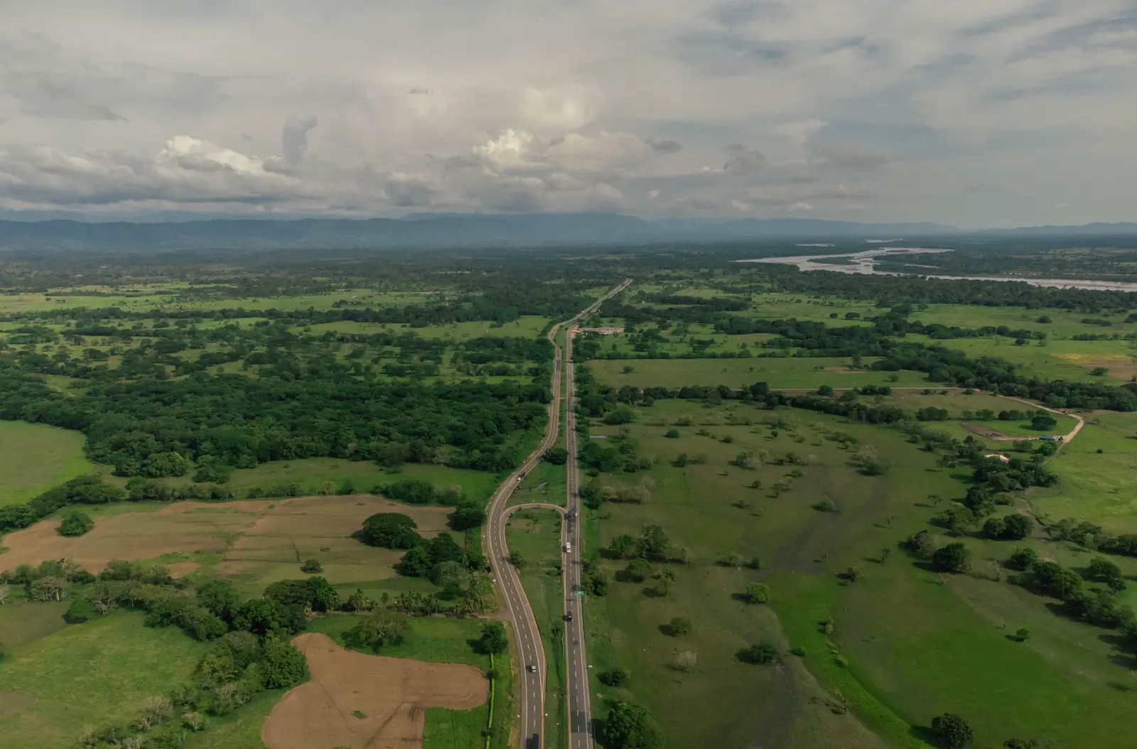 An aerial view of a highway curving through green farmland.